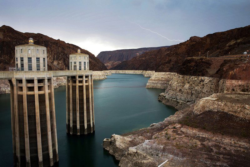 FILE - In this July 28, 2014, file photo, lightning strikes over Lake Mead near Hoover Dam that impounds Colorado River water at the Lake Mead National Recreation Area in Arizona. The Bureau of Reclamation is forecasting first-ever water shortages because of falling levels at Lake Mead and says the reservoir could drop so low that it might not be able to generate electricity at Hoover Dam. (AP Photo/John Locher, File)