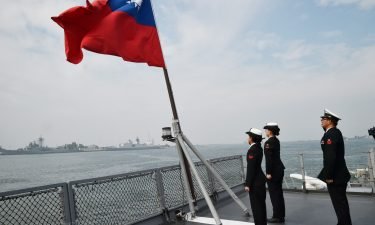Taiwanese sailors salute the island's flag on the deck of the Panshih supply ship after taking part in live fire drills