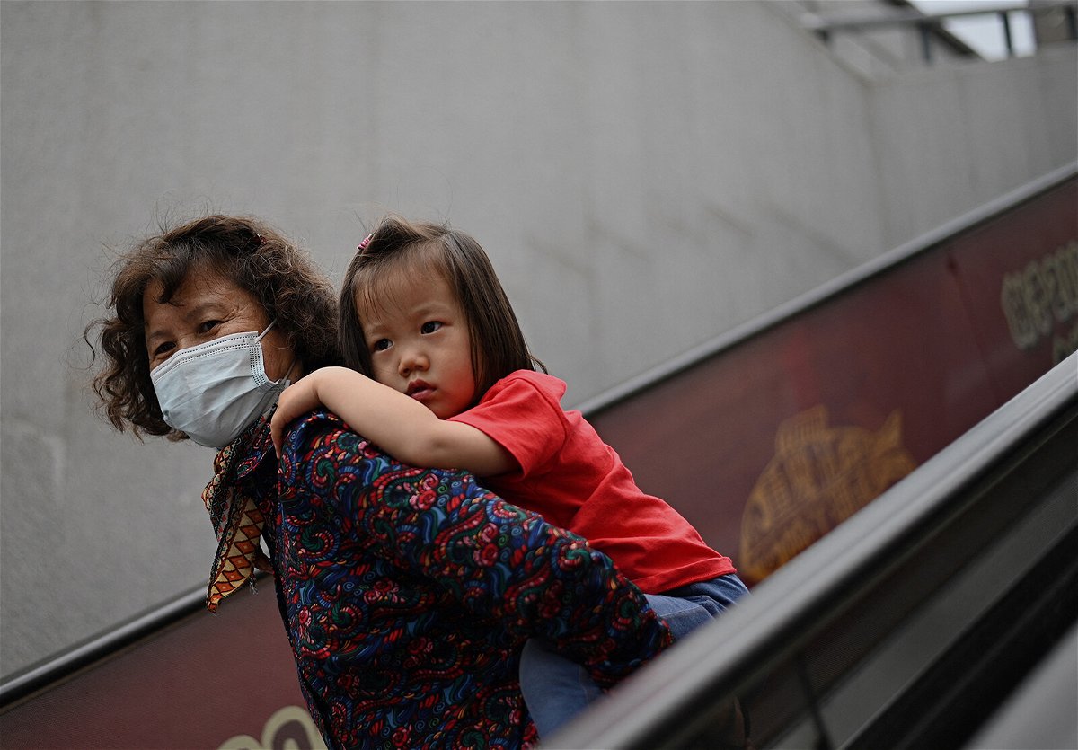 <i>Noel Celis/AFP/Getty Images</i><br/>A girl rides on the back of a woman down an escalator at a shopping centre on International Children's Day in Beijing on June 1