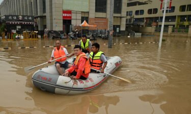 Rescue workers paddle through a flooded street in Zhengzhou