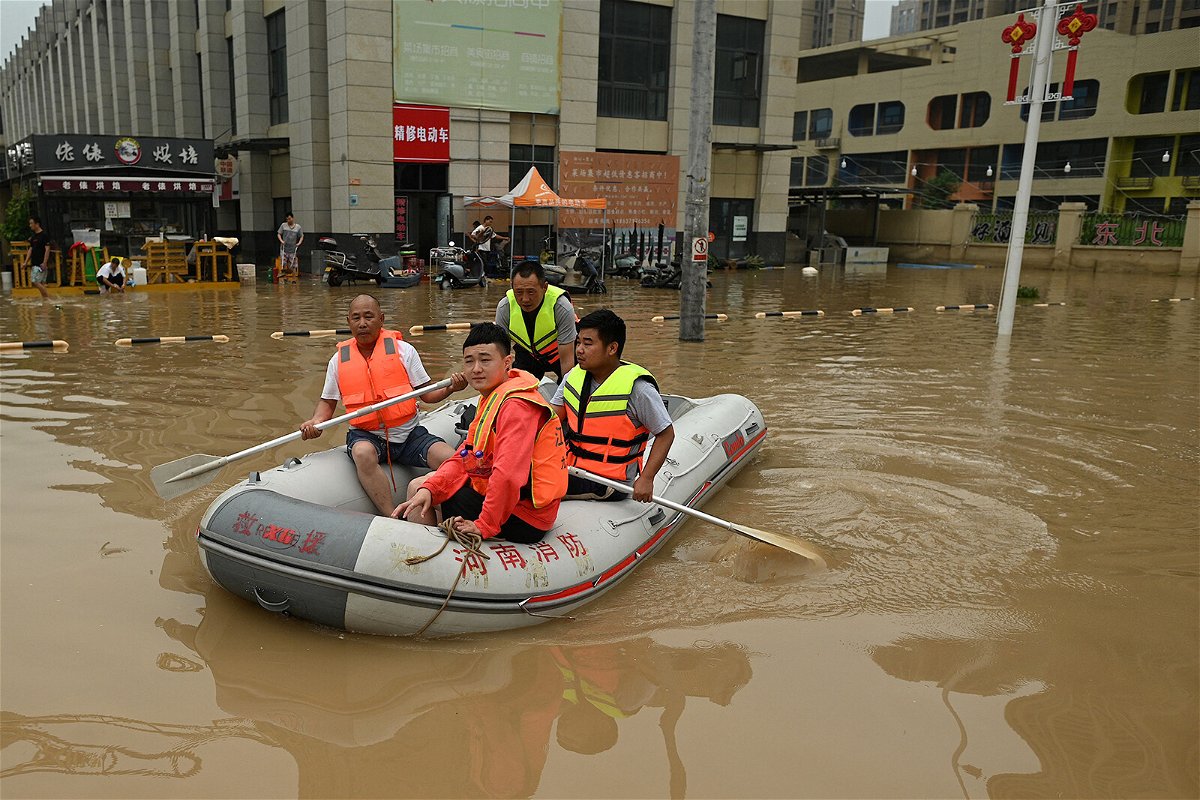 <i>Noel Celis/AFP/Getty Images</i><br/>Rescue workers paddle through a flooded street in Zhengzhou