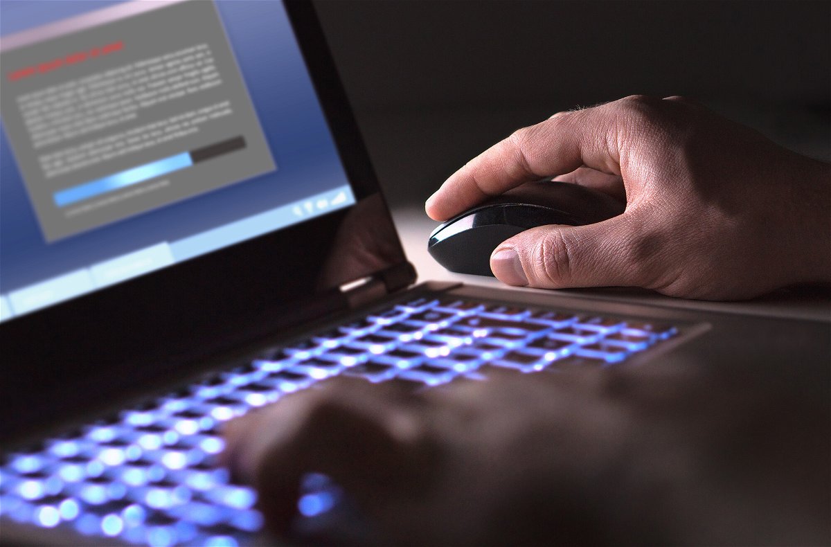 <i>Shutterstock</i><br/>Man installing software in laptop in dark at night.