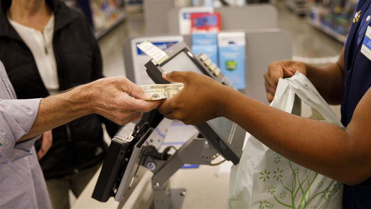 <i>Patrick T. Fallon/Bloomberg/Getty Images</i><br/>A customer hands cash to an employee while making a purchase at a Walmart location in Burbank