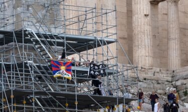 Protesters raise a Tibetan flag and a banner from scaffolding at the Acropolis hill