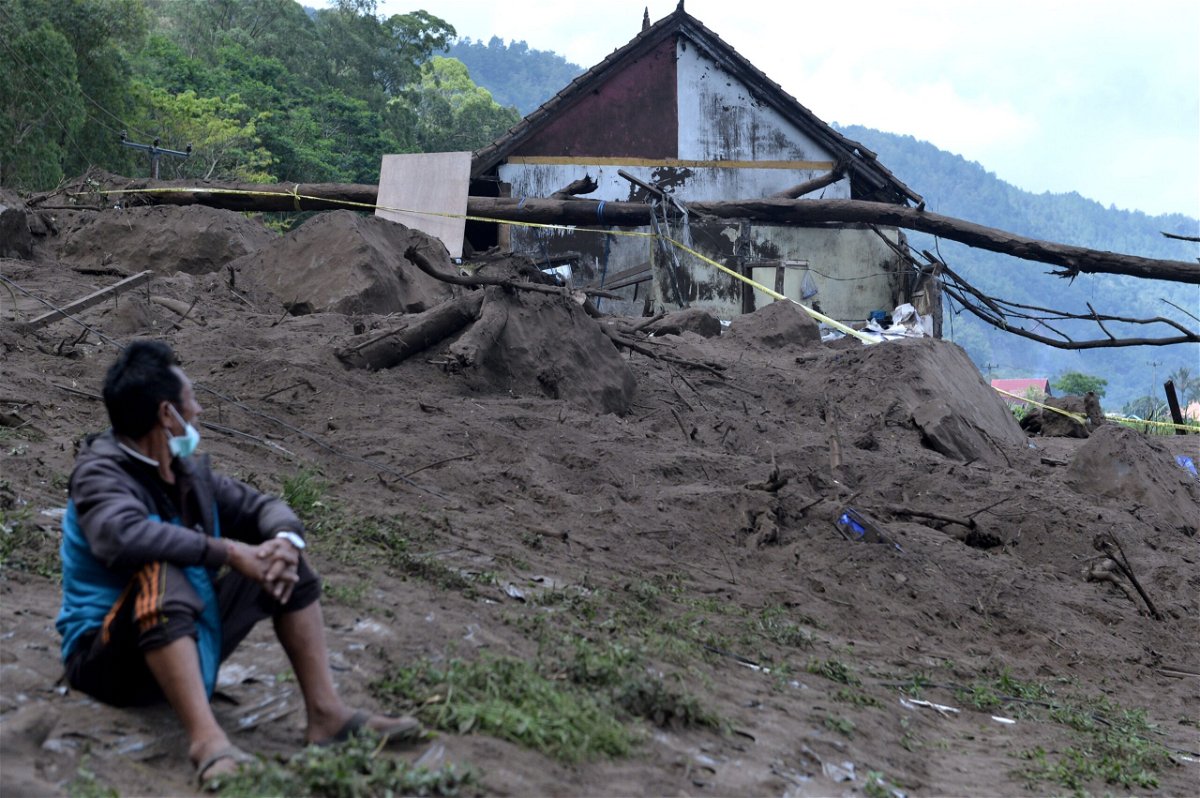 <i>DIMAS DHANI/AFP/AFP via Getty Images</i><br/>A resident sits near houses at the scene of a landslide triggered by a 4.8 magnitude earthquake at Trunyan village in Bangli