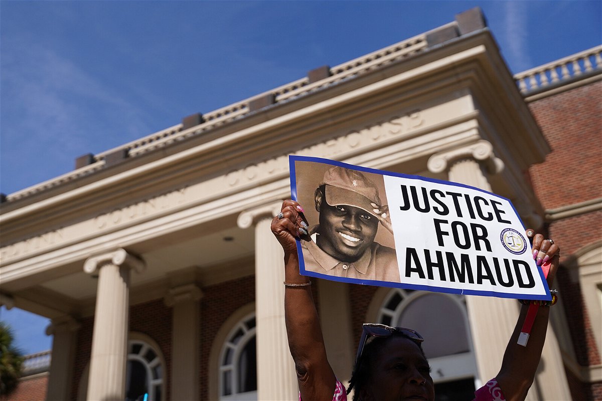 <i>Sean Rayford/Getty Images</i><br/>A demonstrator holds a sign at the Glynn County Courthouse as jury selection begins in the trial of the shooting death of Ahmaud Arbery on October 18