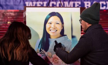 Volunteers attach a photo of Michelle Alyssa Go to the podium before the candlight vigil in her honor in Times Square in New York