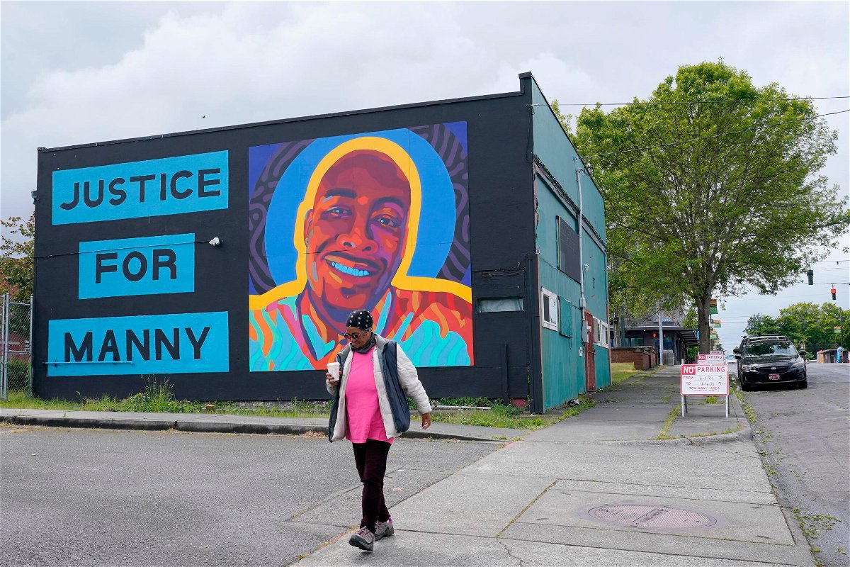 <i>Ted S. Warren/AP</i><br/>A woman walks past a mural honoring Manuel 