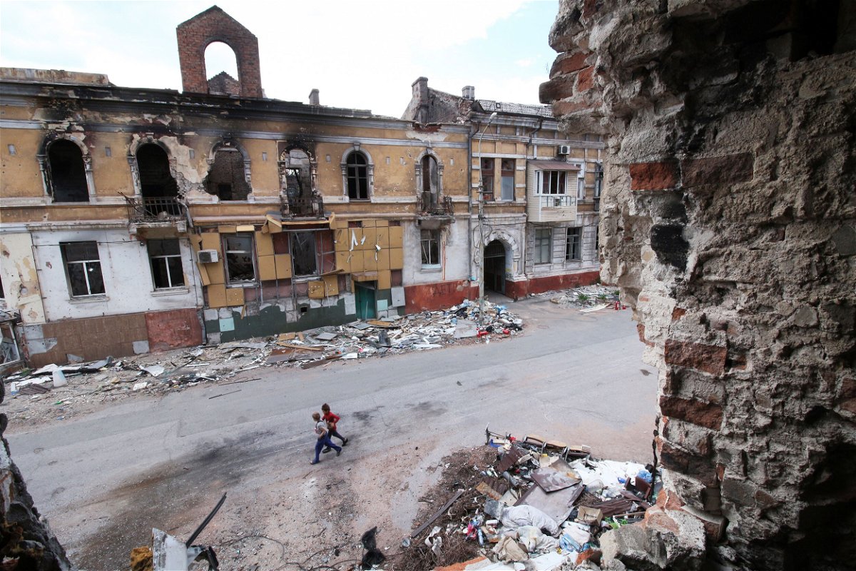 <i>AP</i><br/>Children walk among buildings destroyed during fighting in Mariupol