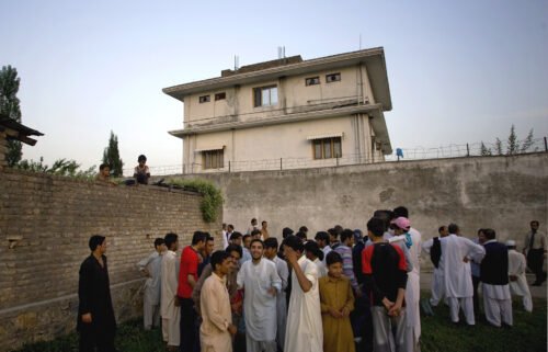 Residents gather outside a house