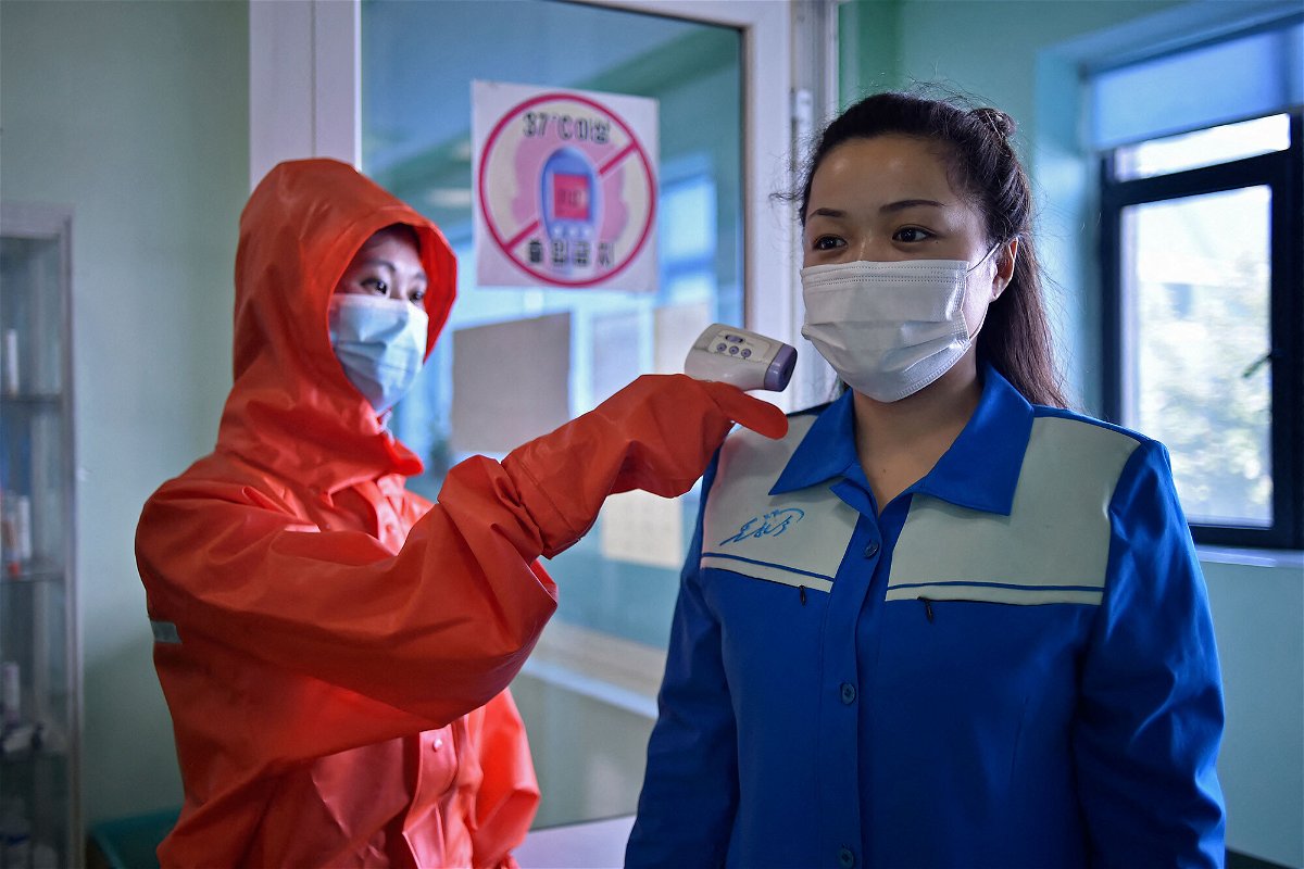 <i>Kim Won Jin/AFP/Getty Images</i><br/>A health worker at the Pyongyang Cosmetics Factory takes the temperature of a woman arriving for her shift on June 16.