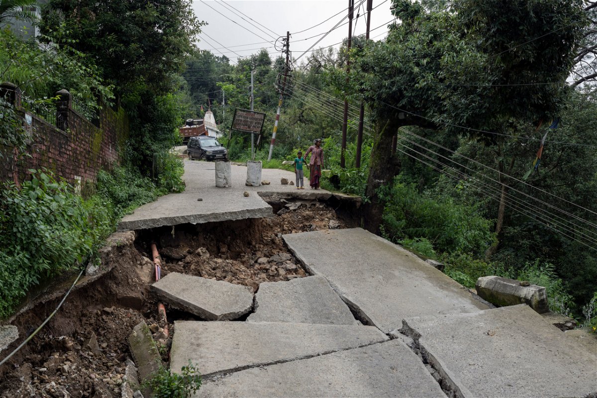 <i>Ashwini Bhatia/AP</i><br/>A woman and child look at a caved-in segment of a road damaged by heavy rain in Dharmsala