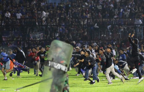 Soccer fans enter the pitch during a clash between supporters at Kanjuruhan Stadium in Malang
