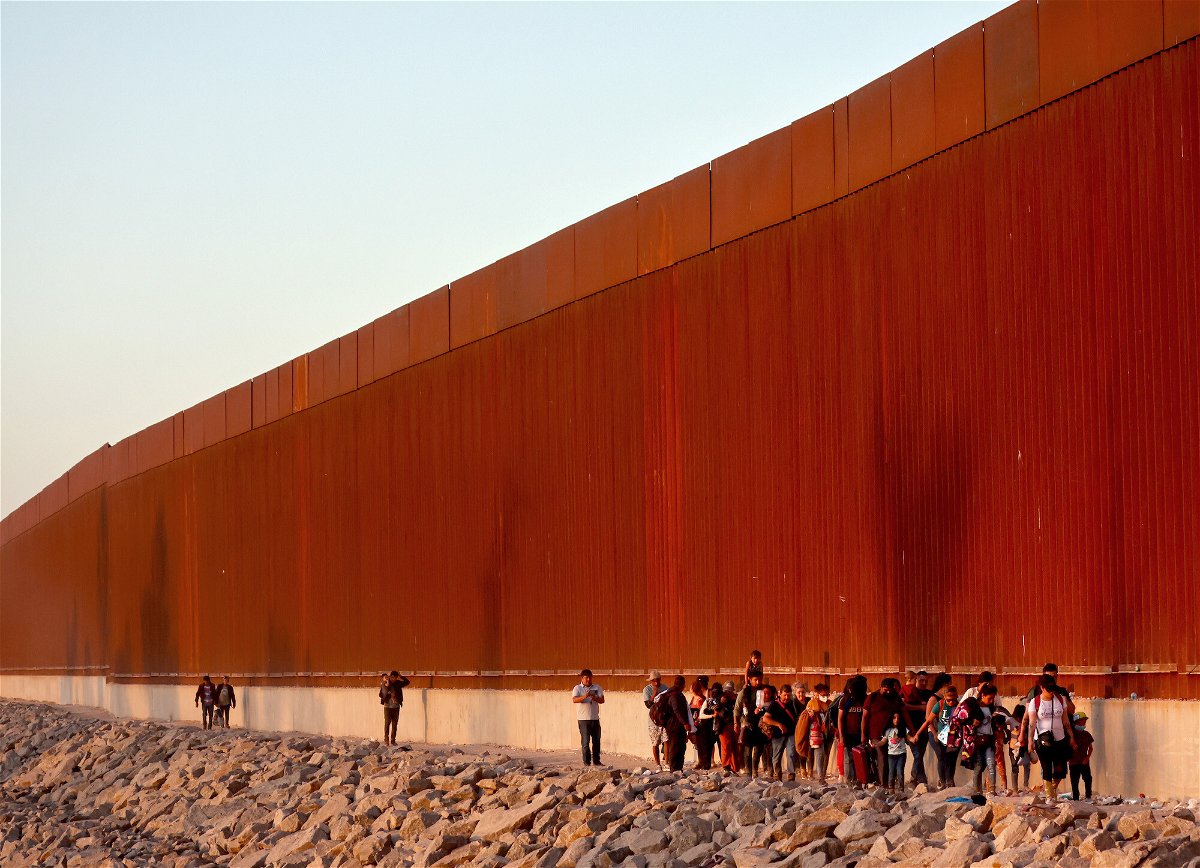 <i>Mario Tama/Getty Images</i><br/>Immigrants walk along the US-Mexico border barrier on their way to await processing by the Border Patrol after crossing from Mexico on May 21