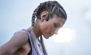 A woman wearing bone conduction headphones by Shokz is seen here.