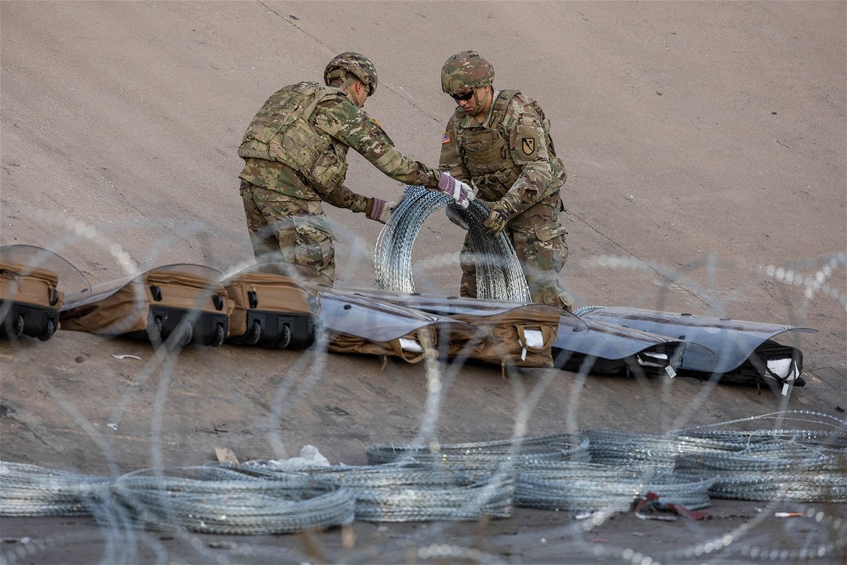 <i>John Moore/Getty Images</i><br/>Texas National Guard troops unroll coils of concertina wire Wednesday near the US-Mexican near Ciudad Juarez.