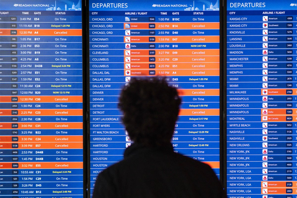 <i>Mandel Ngan/AFP/Getty Images</i><br/>Travelers look at an information board showing flight cancellations and delays at Reagan National Airport in December 2022. The Department of Transportation's internal watchdog said on February 21 it is launching a probe into the spike in flight cancellations and delays.
