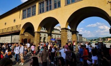 People walk on the Ponte Vecchio onto Arno river