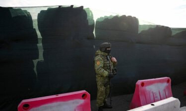A Belarusian border guard keeps watch and stands by a barricade made of truck tyres at the Divin border crossing point between Belarus and Ukraine in the Brest region on February 15.