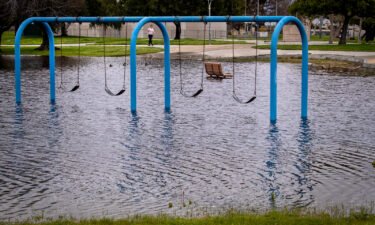 A person walks past a flooded playground section in Huntington Beach Monday