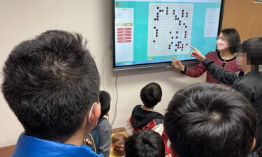 Ao Lixian and her students discuss strategy at Hong Kong Children's Go College (CNN blurred portions of the image to protect a child's identity).
