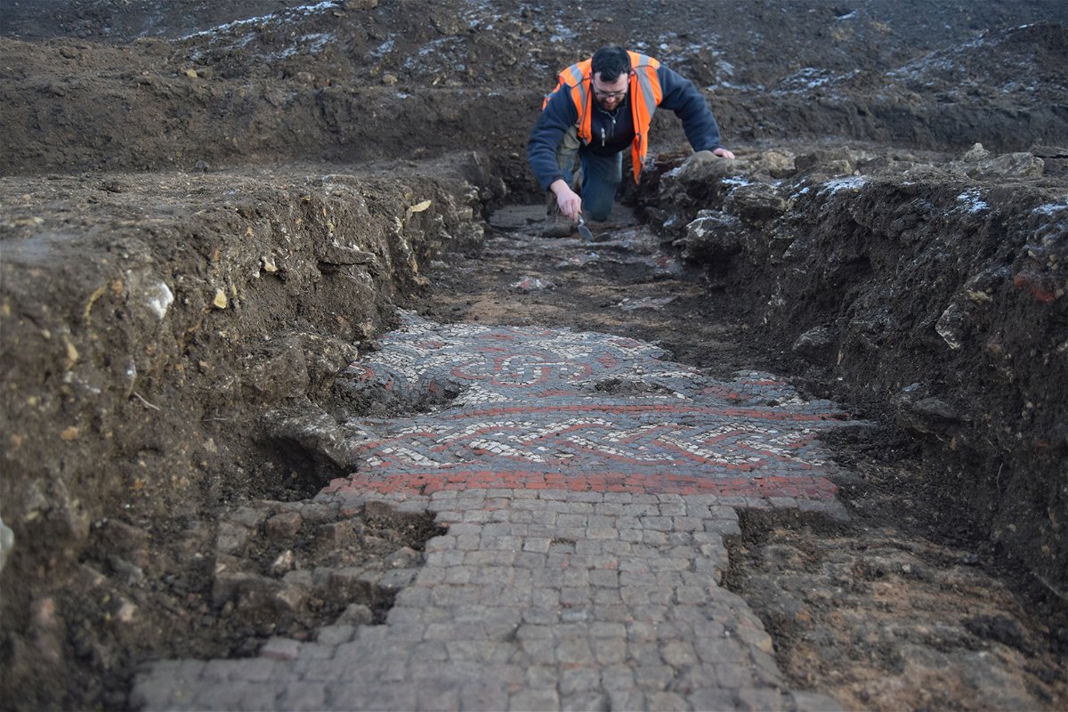 <i>Courtesy Oxford Archaeology</i><br/>A member of the team cleaning the borders of the mosaic.