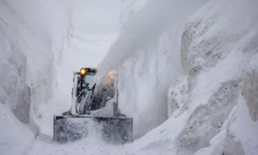 A tractor blows snow from a street that is walled in by snow as it continues to deepen in the first days of spring on March 21