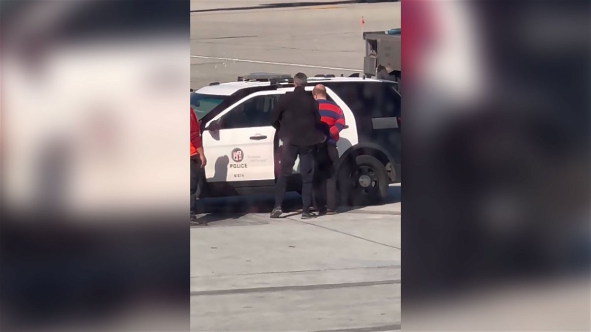 <i>Gillian Sheldon</i><br/>A  passenger is taken into custody after opening a door of a Boeing 737 and deploying an emergency exit slide Sunday at Los Angeles International Airport.