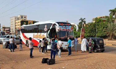 People wait to board a bus on Tuesday in Sudan's capital