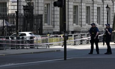 Police officers stand near the car that was driven into the gates of 10 Downing Street.