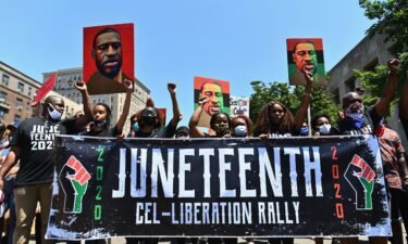 Demonstrators at a 2020 Juneteenth rally in New York hold up pictures of George Floyd.