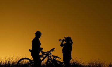 Cyclists take a water break on a June 2023 evening ride during a heat wave in San Antonio.