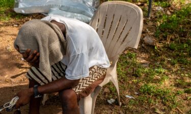 A man sits with a towel over his head in the shade on June 19 in Austin