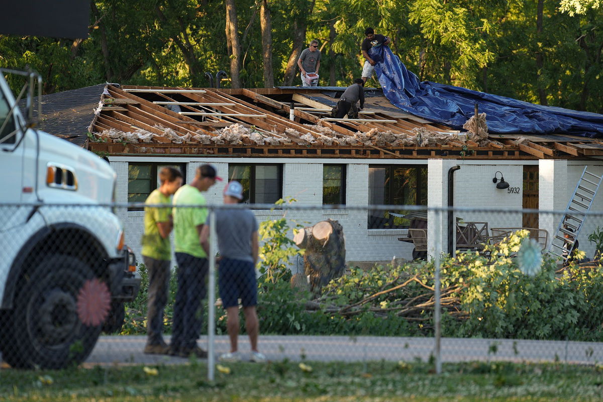 <i>Jenna Watson/The Indianapolis Star/AP</i><br/>Workers put a tarp over a damaged roof after a reported tornado touched down in Johnson County