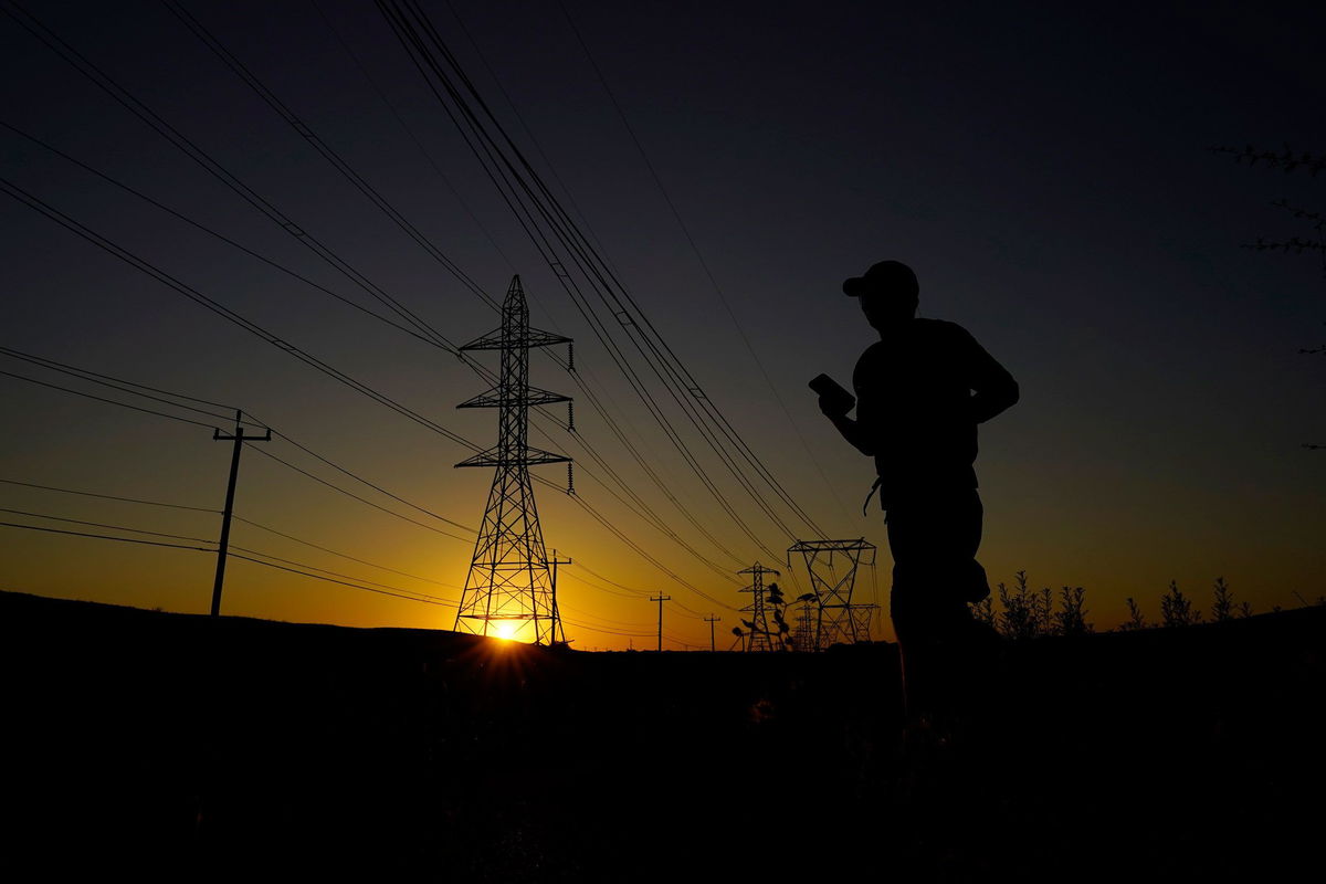 <i>Eric Gay/AP</i><br/>A jogger passes under power lines during an evening run on Monday in San Antonio. Nighttime temperatures will stay dangerously hot this week