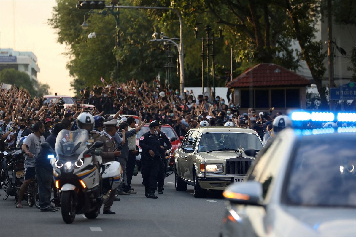 The royal motorcade carrying Thailand's Queen Suthida and Prince Dipangkorn drives past a group of anti-government demonstrators in Bangkok in October 2020.