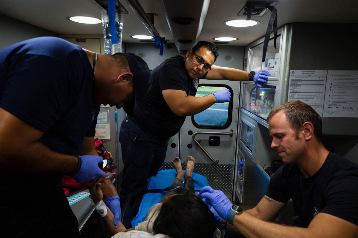<i>Kaylee Greenlee Beal/Reuters</i><br/>A firefighter EMT team treats a migrant woman suffering from heat exhaustion in the border community of Eagle Pass