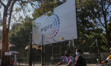Motorcyclists drive past a Wipro Ltd. sign in the Electronic City area of Bengaluru