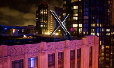 Workers install lighting on an "X" sign atop the company headquarters