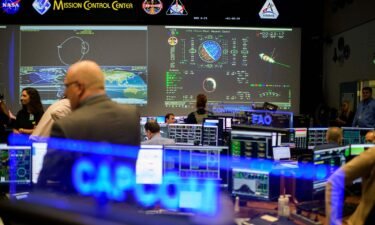 People walk through the White Flight Control Room at the Johnson Space Center's Mission Control Center in Houston