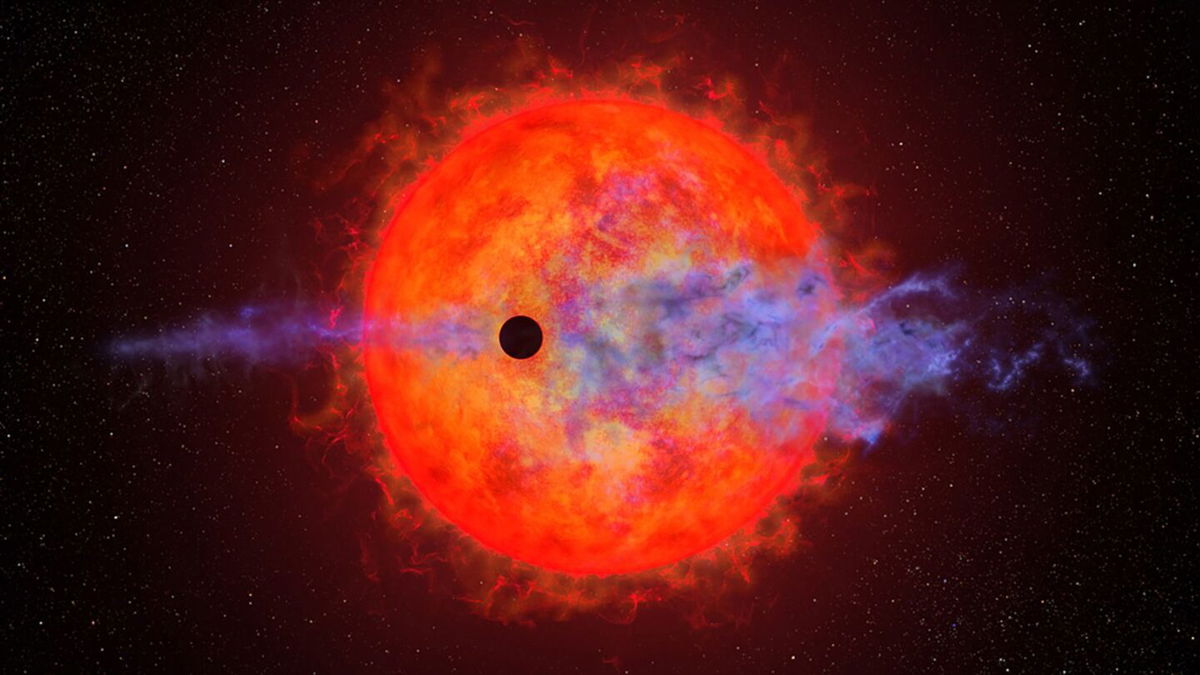 <i>NASA/ESA/Joseph Olmsted (STScI)</i><br/>This artist's illustration shows the shadow of a planet passing in front of the red dwarf star AU Microscopii. Blue clouds depict the planet's atmosphere