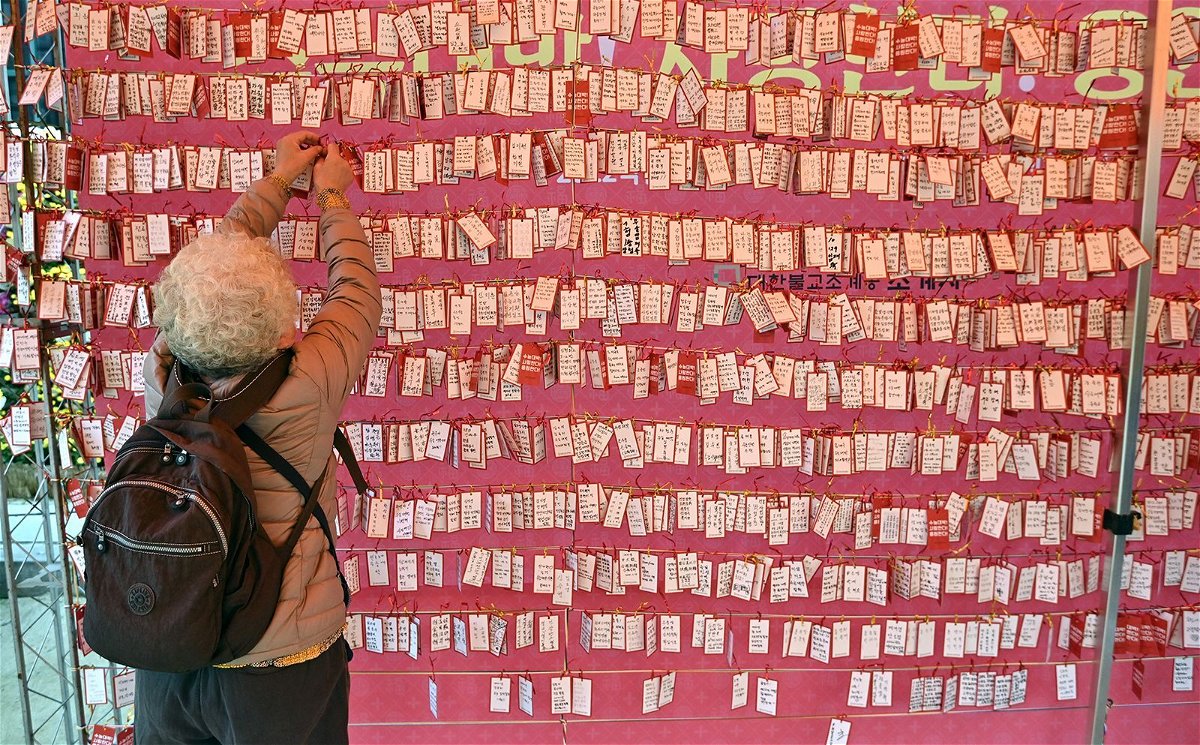A woman attaches a name card wishing for good results for students in South Korea's college entrance exam
