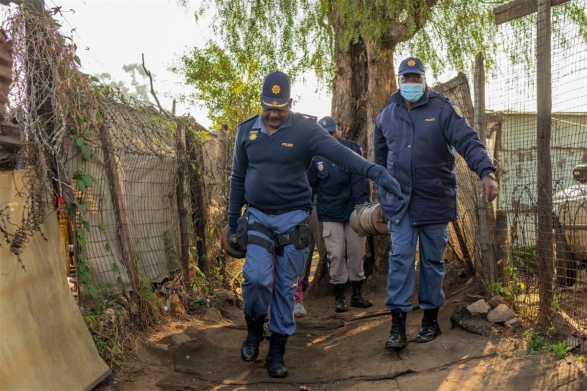 South African police officers remove gas cylinders used by illegal gold miners in the Angelo Informal Settlement in Boksburg