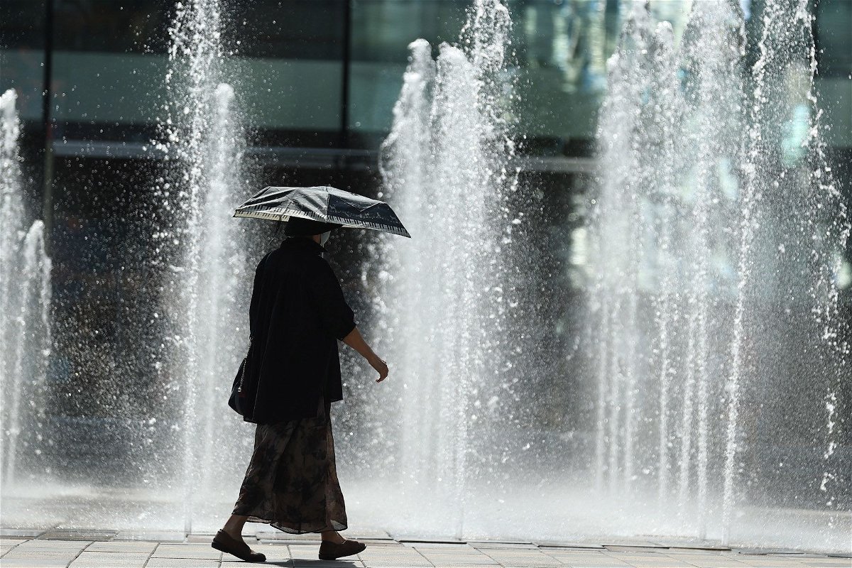 A pedestrian uses an umbrella to shade from the sun during a heat wave in Beijing on July 6