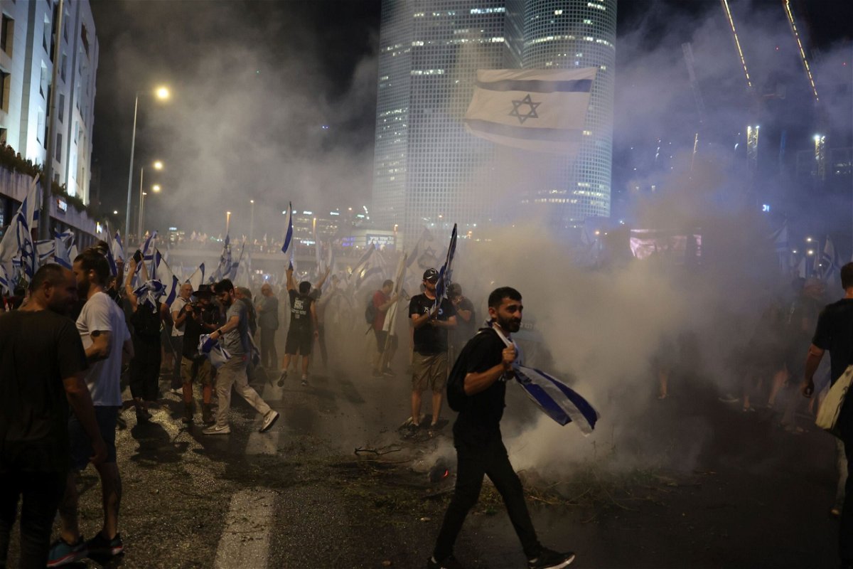 Israeli demonstrators hold flags and burn flares as they block the Ayalon highway.