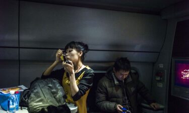 A woman puts on make-up at a railway station in Beijing on December