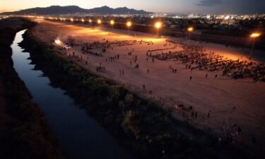 Migrants gather near the border wall after crossing the Rio Bravo river with the intention of turning themselves in to the U.S. Border Patrol agents to request asylum