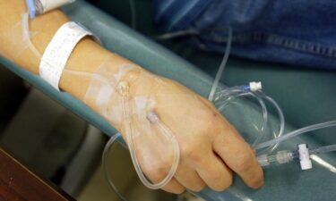 A cancer patient holds the IV tubes during chemotherapy.