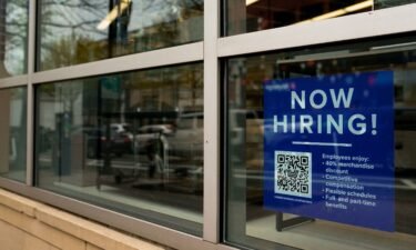 An employee hiring sign with a QR code is seen in a window of a business in Arlington