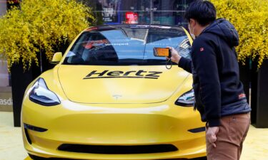 A man photographs a Hertz Tesla electric vehicle displayed during the Hertz Corporation IPO at the Nasdaq Market site in Times Square in New York City.